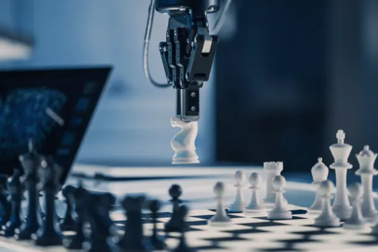 Robot holding a white chess piece above a chess board.